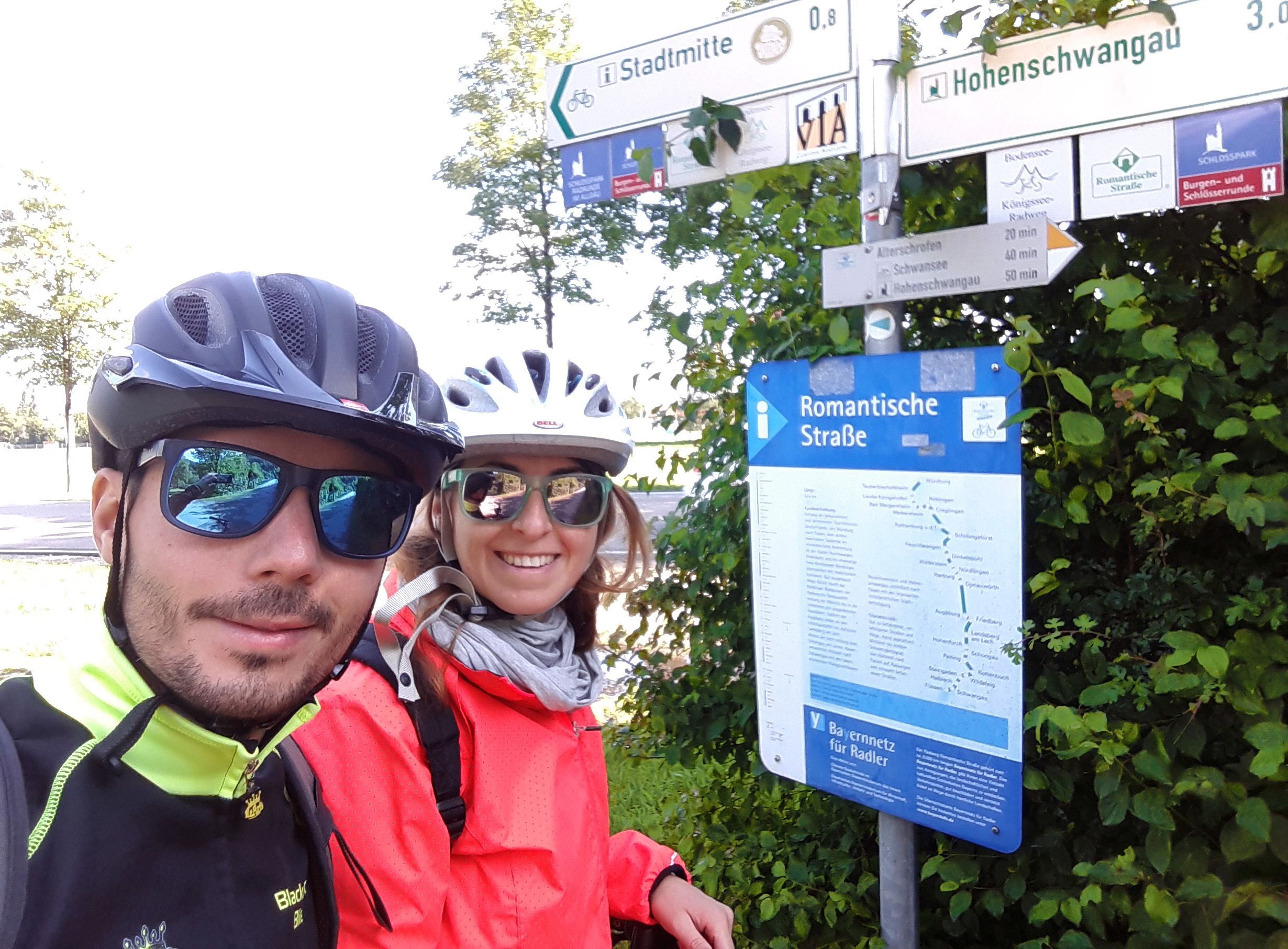Ciclisti vicino a un segnale turistico della Romantische Strasse, vacanze in bici "Girolibero"